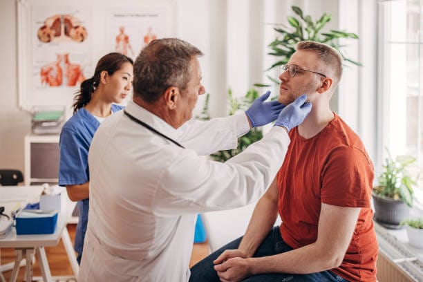 GP examining swollen neck glands caused by glandular fever (Epstein-Barr virus)
